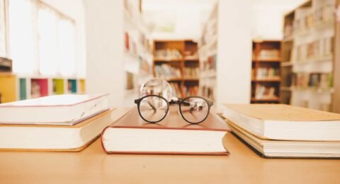 Book in library with old open textbook, stack piles of literatur